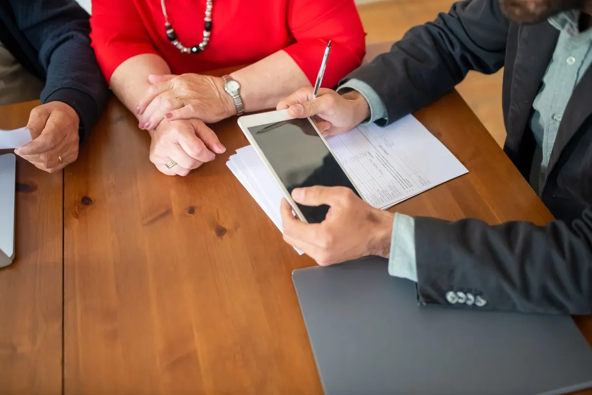 Conseiller en assurance étudiant des documents avec un client autour d'une table en bois