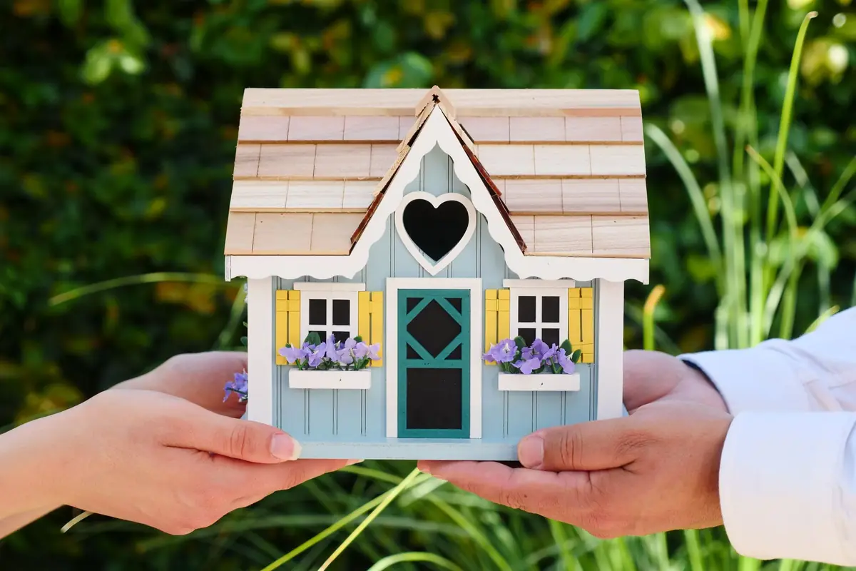 Mains tenant un modèle réduit de maison, symbole d'un projet de construction