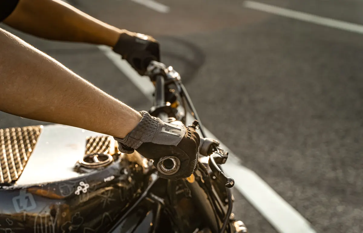 Mains gantées d'un motard sur le guidon pendant la conduite, en lumière chaude