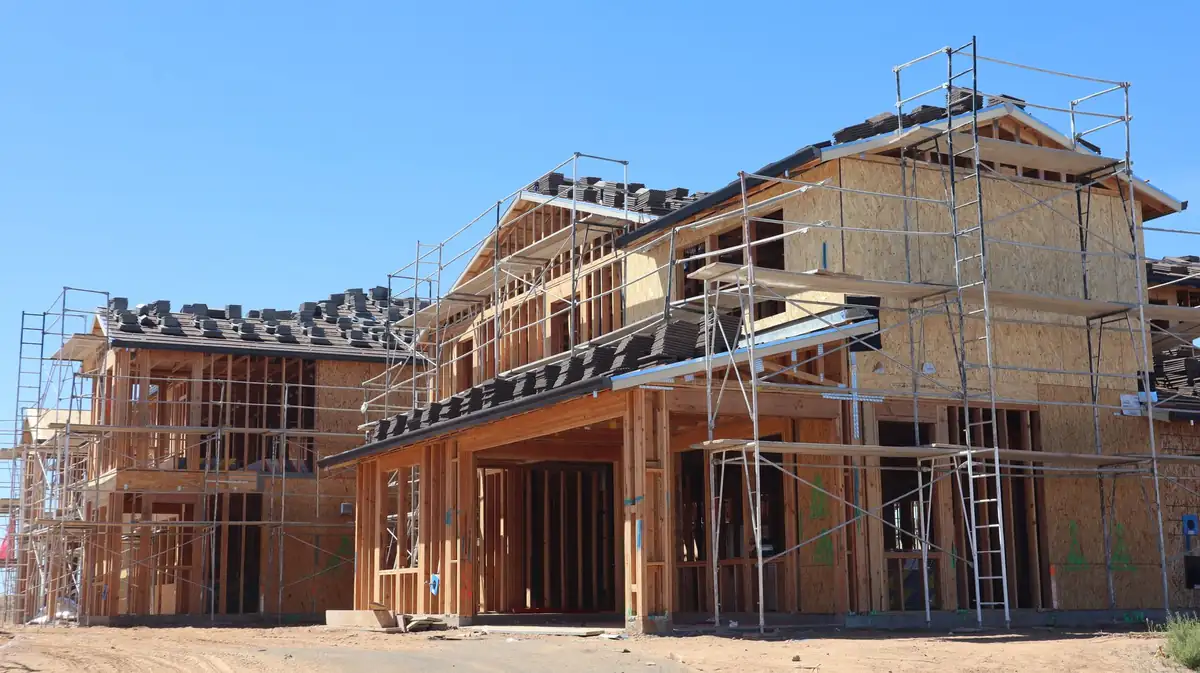 Maisons neuves en cours de construction, ossature bois et échafaudages sous un ciel bleu