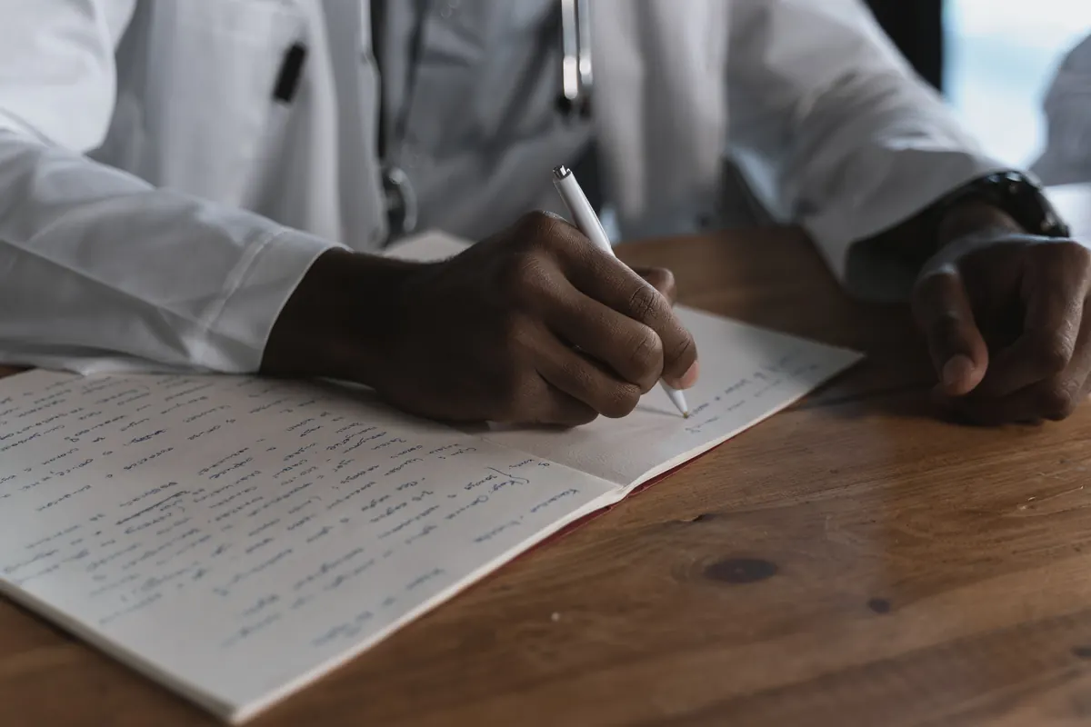 Médecin rédigeant une ordonnance sur un bureau en bois, remboursement des soins
