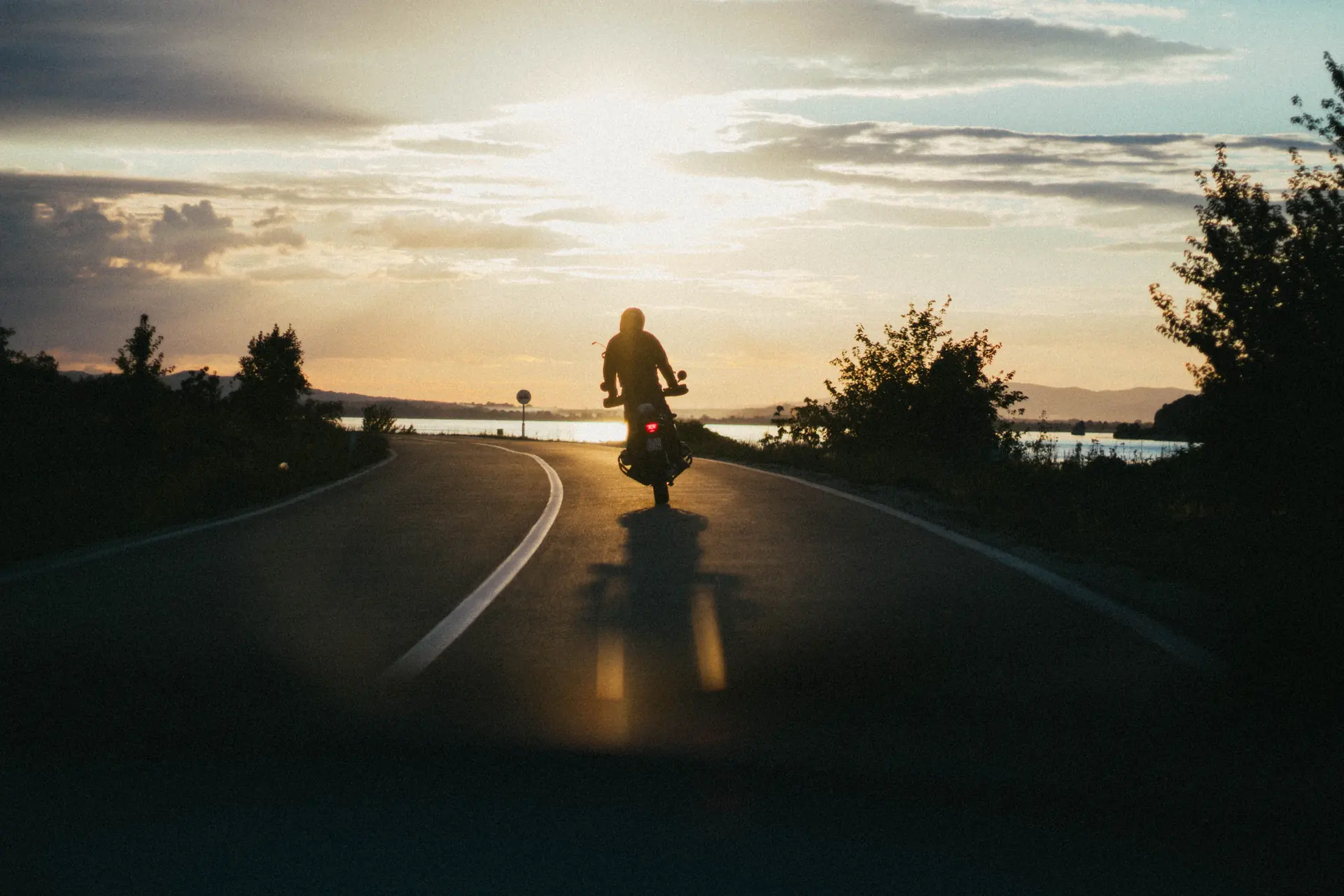 Motard roulant sur une route sinueuse au coucher du soleil