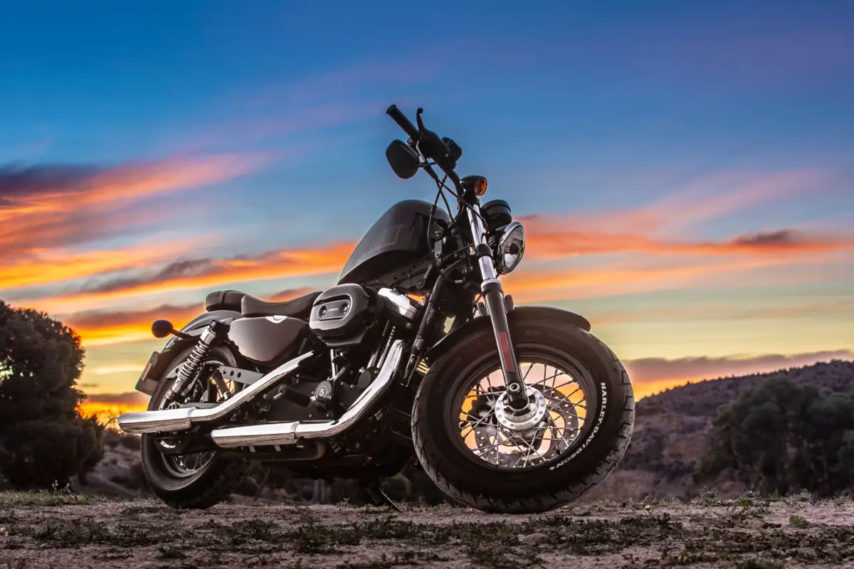 Moto custom chromée sur un chemin de terre sous un ciel de coucher de soleil, devis assurance moto