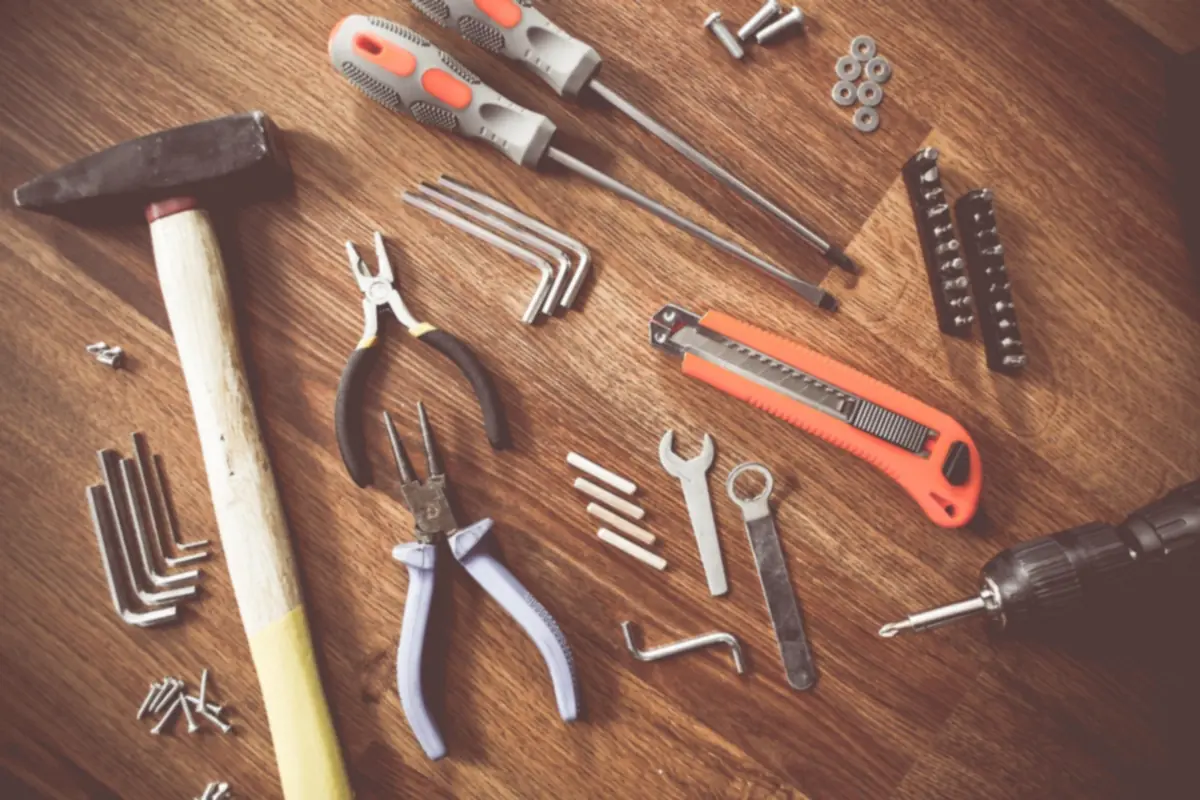 Outils d'artisan du bâtiment posés sur un établi en bois : marteau, pinces, tournevis et clés