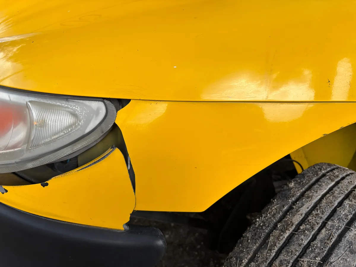 Pare-chocs et phare endommagés d'une voiture jaune après un sinistre