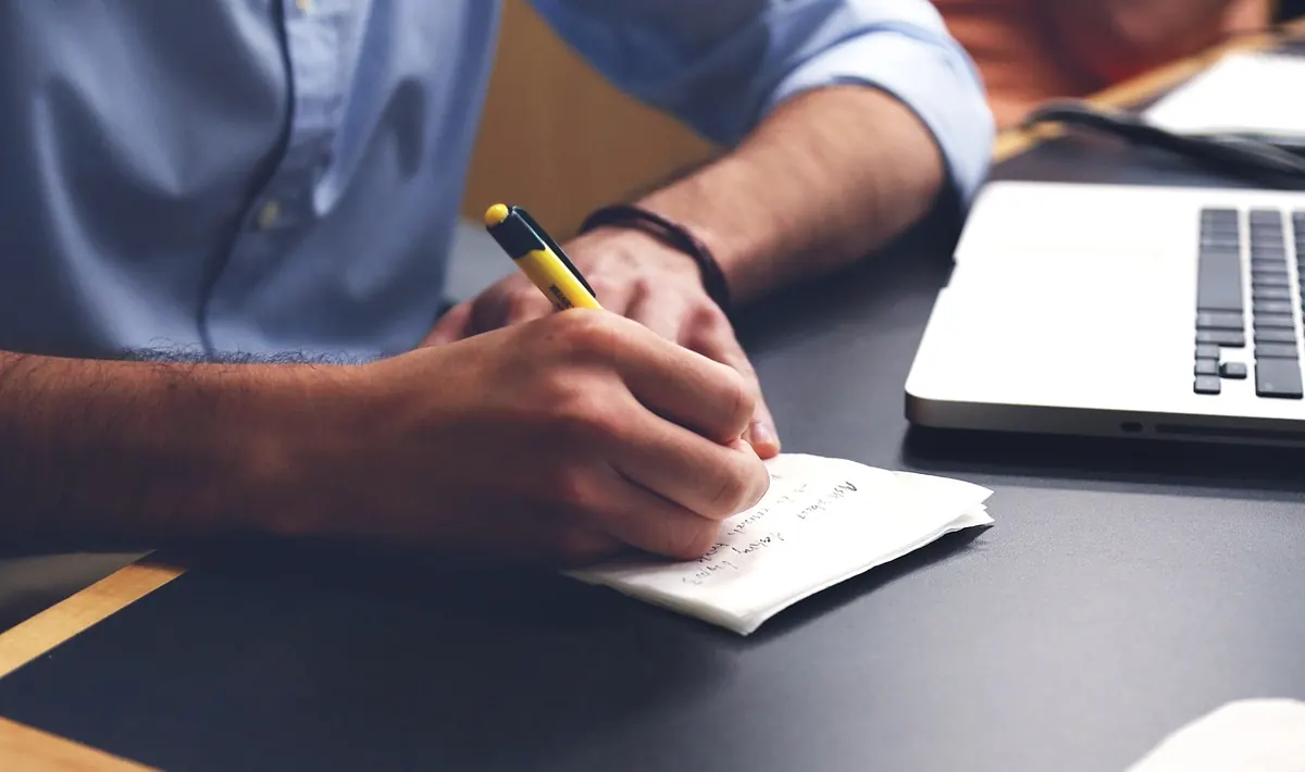 Personne prenant des notes à son bureau pour préparer une demande de devis