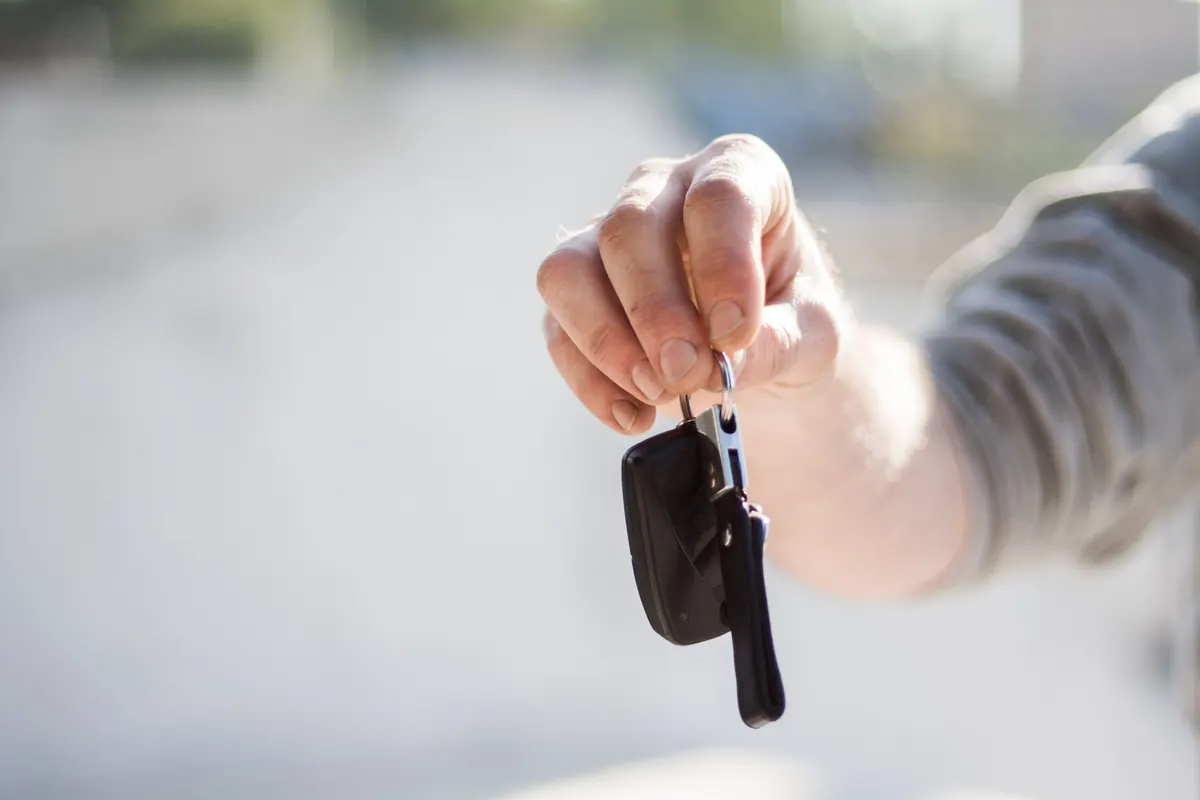 Main remettant une clé de voiture, reprendre la route avec un nouveau contrat d'assurance