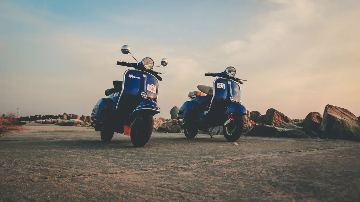 Deux scooters bleus garés en bord de mer au coucher du soleil, assurance scooter