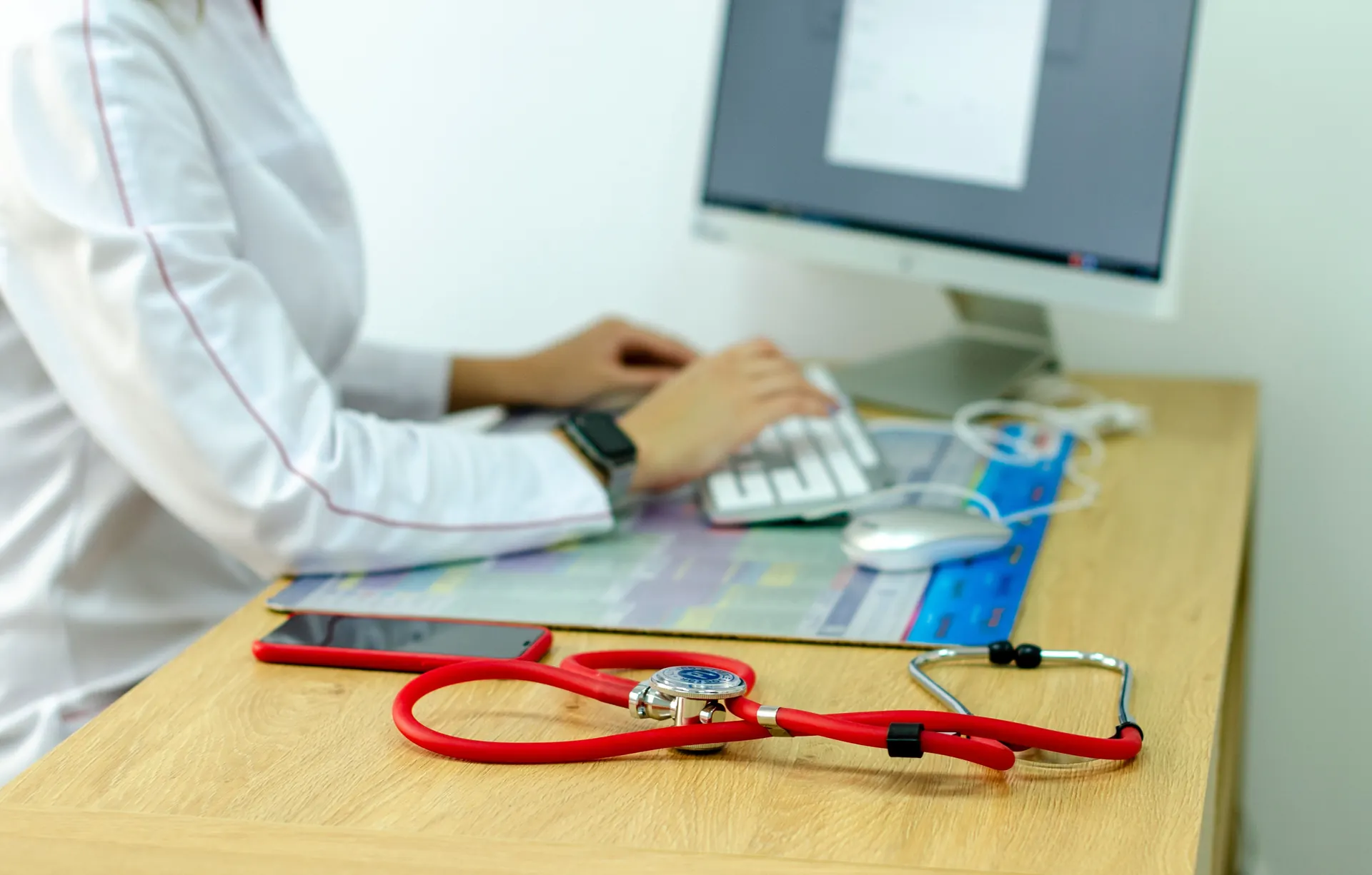 Stéthoscope rouge posé sur le bureau en bois d'un médecin