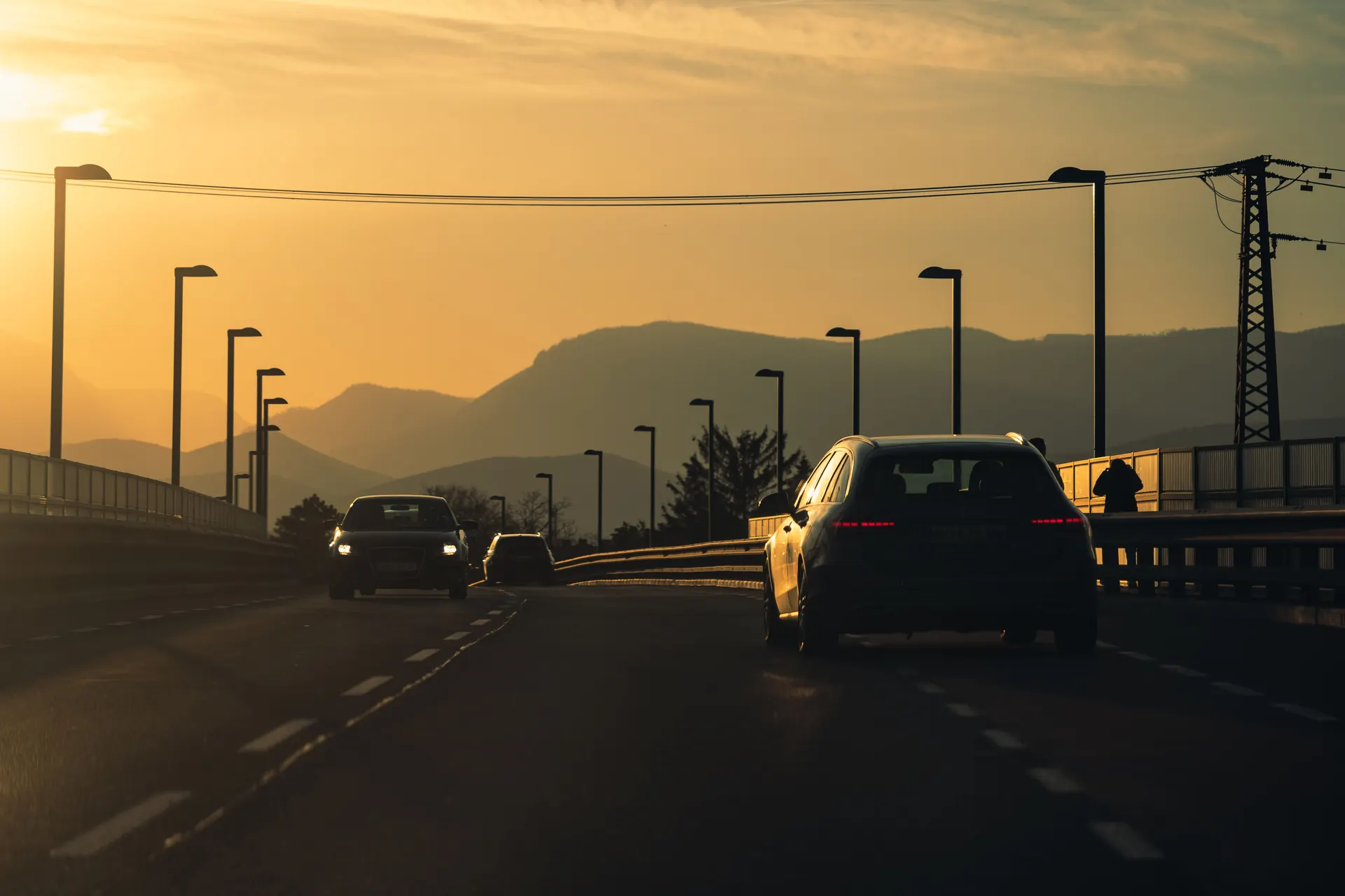 Voitures roulant sur une route au coucher du soleil face aux montagnes